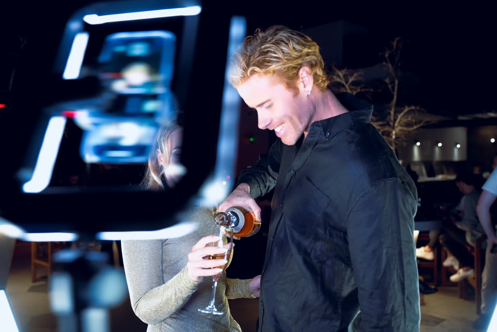 A guest pouring champagne, photographed with flash at a night event